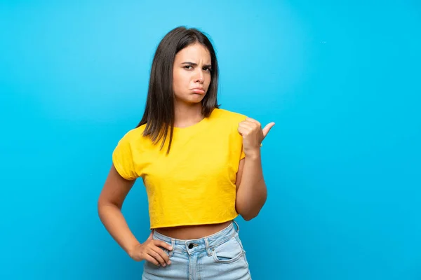 Menina Sobre Isolado Fundo Azul Infeliz Apontando Para Lado — Fotografia de Stock