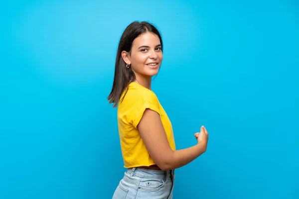 Chica Joven Sobre Fondo Azul Aislado Apuntando Hacia Atrás — Foto de Stock