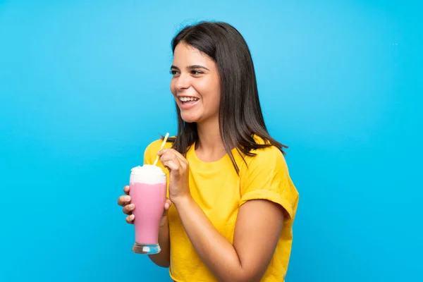 Ung flicka med jordgubbs milkshake över isolerad blå bakgrund — Stockfoto