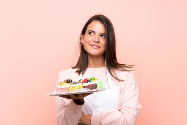 Junges Mädchen Hält Viele Verschiedene Mini Kuchen Über Isoliertem Hintergrund — Stockfoto