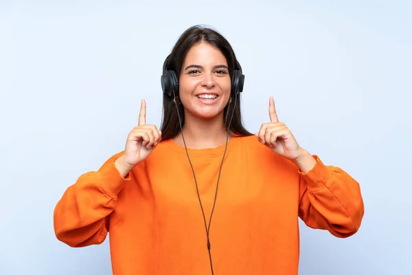 Mujer Joven Escuchando Música Con Móvil Sobre Una Pared Azul —  Fotos de Stock