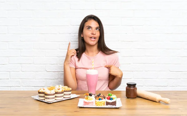 Junges Mädchen Mit Vielen Verschiedenen Mini Kuchen Mit Überraschendem Gesichtsausdruck — Stockfoto