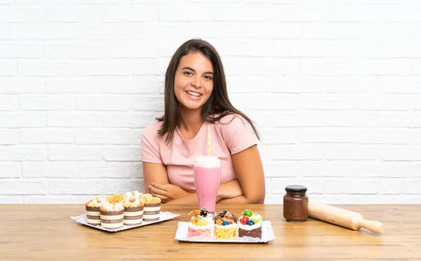 Junges Mädchen Mit Vielen Verschiedenen Mini Kuchen Lacht — Stockfoto