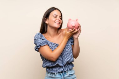 Büyük bir kumbara tutan izole arka plan üzerinde genç kız