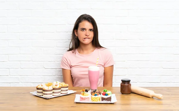 Junges Mädchen Mit Vielen Verschiedenen Mini Kuchen Mit Zweifeln Und — Stockfoto