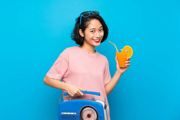 Ασιάτης/ισσα νεαρή γυναίκα πάνω από απομονωμένο μπλε φόντο κρατώντας ένα ραδιόφωνο — Φωτογραφία Αρχείου