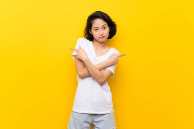Asya genç kadın üzerinde izole sarı duvar lateraller şüphe sahip işaret