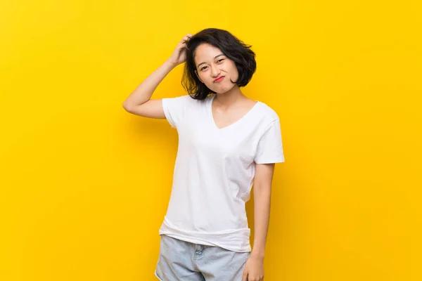 Asian Young Woman Isolated Yellow Wall Having Doubts While Scratching — Stock Photo, Image
