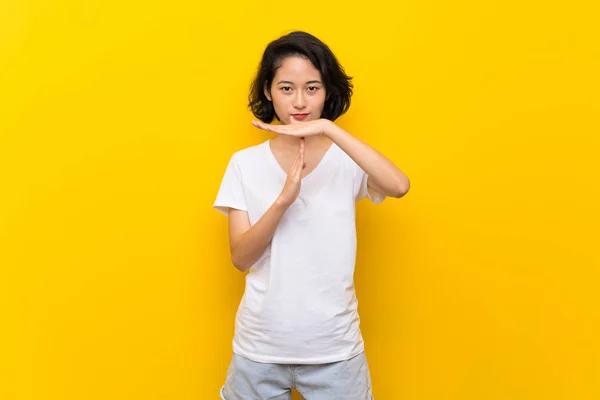 Asiatisk Ung Kvinde Isoleret Gul Væg Gør Tid Gestus - Stock-foto