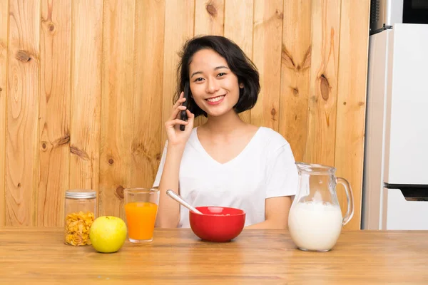 Asiatische junge Frau frühstückt und hält ein Gespräch mit dem Handy — Stockfoto