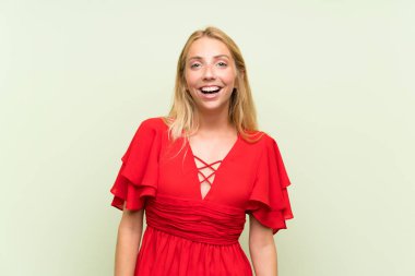 Sürpriz yüz ifadesi ile izole yeşil arka plan üzerinde Sarışın genç kadın