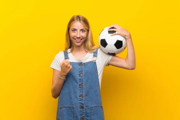 Loira Jovem Sobre Isolado Fundo Amarelo Segurando Uma Bola Futebol — Fotografia de Stock