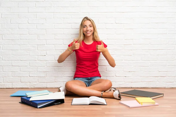 Joven Estudiante Rubia Con Muchos Libros Suelo Dando Gesto Pulgares — Foto de Stock