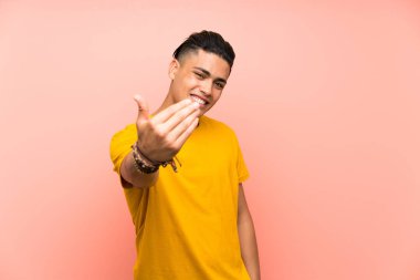 Izole pembe duvar üzerinde sarı gömlekli genç adam gelmeye davet