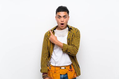 Izole beyaz duvar üzerinde genç elektrikçi adam şaşırttı ve tarafı işaret