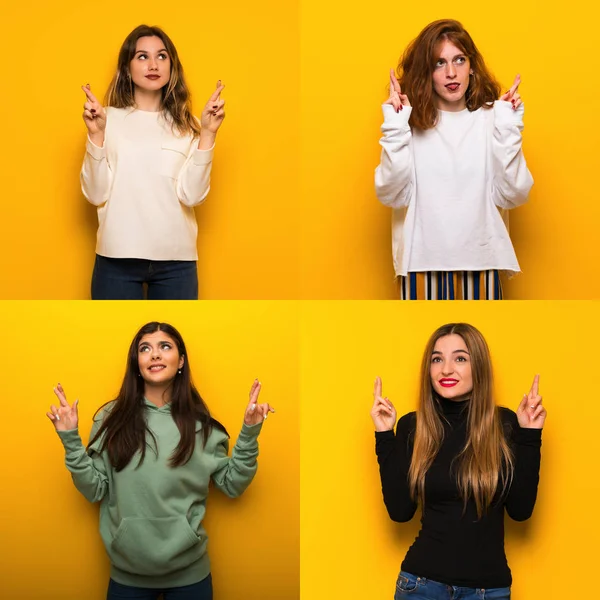 Set of women over Yellow background with fingers crossing and wishing the best