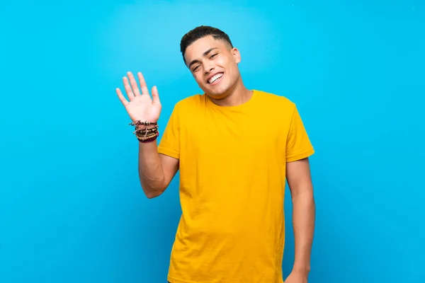 Молодий Чоловік Жовтою Сорочкою Над Ізольованим Синім Фоном Рукою Щасливим — стокове фото