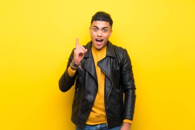 Izole sarı arka plan üzerinde genç adam bir fikir parmağını işaret düşünme