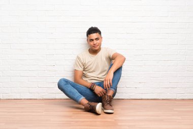 Genç adam ayakta katta oturan ve yan bakıyor