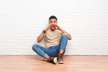 Yerde oturan genç adam ağzı tamamen açık bağırarak