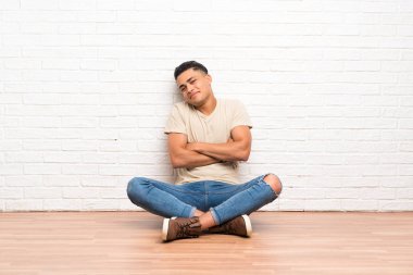 Genç adam yerde oturmuş gülüyor.