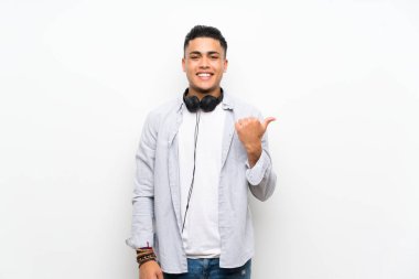 Bir ürün sunmak için yan işaret kulaklık ile izole beyaz duvar üzerinde genç adam