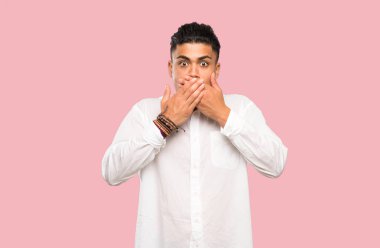 Renkli arka plan üzerinde elleri ile ağız kapsayan genç adam