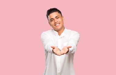 Renkli arka plan üzerinde bir reklam eklemek için avuç üzerinde copyspace hayali tutan genç adam