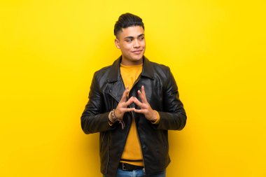 Izole sarı arka plan üzerinde genç adam bir şey entrika