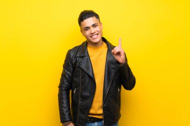 Izole sarı arka plan üzerinde genç adam gösteren ve en iyi işareti bir parmak kaldırma