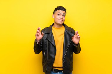 Parmakları geçiş ve en iyi dilek ile izole sarı arka plan üzerinde genç adam