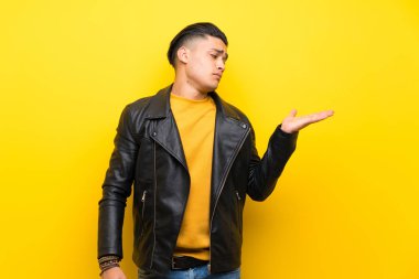 Şüphelerle copyspace tutan izole sarı arka plan üzerinde genç adam