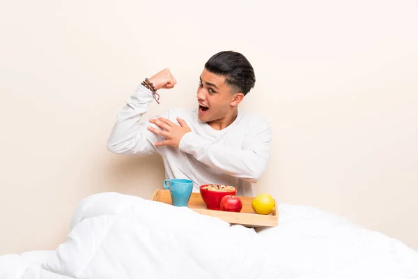 Joven Desayunando Cama Haciendo Gesto Fuerte —  Fotos de Stock