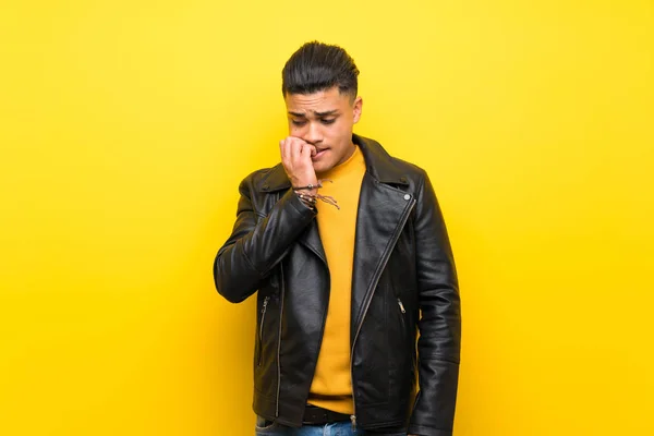 Young man over isolated yellow background having doubts