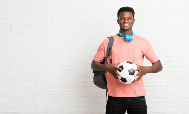 Genç afro Amerikan adam öğrenci bir futbol topu tutan