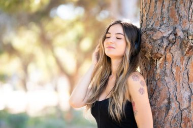 Bir parkta müzik dinleyen açık havada genç kız