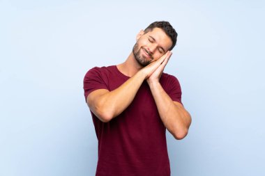 İzole mavi arka plan üzerinde Dorable ifade uyku jest yapma yakışıklı adam