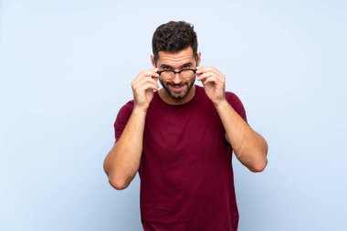 Gözlük ve şaşırttı ile izole mavi arka plan üzerinde Yakışıklı adam