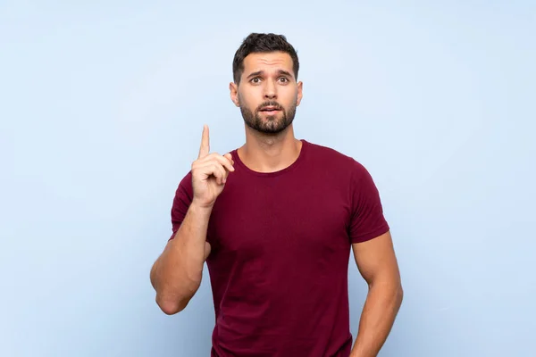 Hombre Guapo Sobre Fondo Azul Aislado Pensando Una Idea Apuntando — Foto de Stock