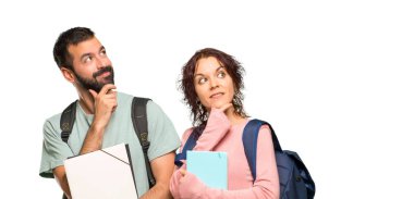 Sırt çantaları ve kitapları ile izole beyaz arka plan üzerinde bir fikir düşünme iki öğrenci