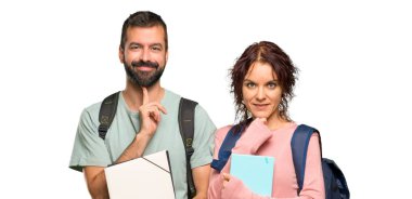 Sırt çantaları ve kitapları ile iki öğrenci gülümseyerek ve izole beyaz arka plan üzerinde emin bir yüz ile ön bakıyor