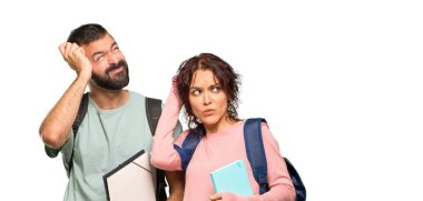 Sırt çantaları ve kitapları olan iki öğrenci şüpheleri ve izole beyaz arka plan üzerinde başını çizerken yüzünü karıştırarak