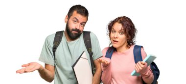 Sırt çantaları ve kitapları olan iki öğrenci şüpheleri ve izole beyaz arka plan üzerinde yüz ifadesi karıştırmak ile