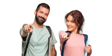 Sırt çantaları ve kitapları olan iki öğrenci, izole edilmiş beyaz arka plan da kendine güvenen bir ifadeyle sizi işaret ediyor