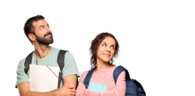 Izole beyaz arka plan üzerinde gülümseyerek sırt çantaları ve kitaplar ile iki öğrenci