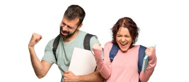 Sırt çantaları ve kitapları ile iki öğrenci bir zafer kutluyor ve izole beyaz arka plan üzerinde bir ödül kazanmış olması için mutlu