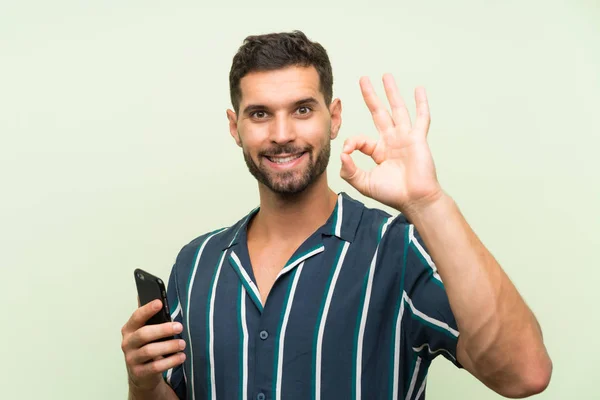 Junger Gutaussehender Mann Mit Handy Zeigt Zeichen Mit Fingern — Stockfoto