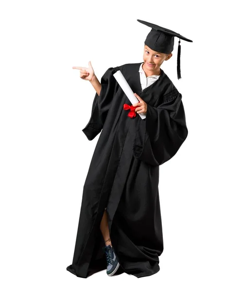 Full body of Little boy graduating pointing finger to the side and presenting a product on isolated white background