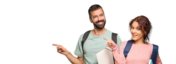 Sırt Çantaları Kitapları Ile Iki Öğrenci Yan Parmak Işaret Izole — Stok fotoğraf