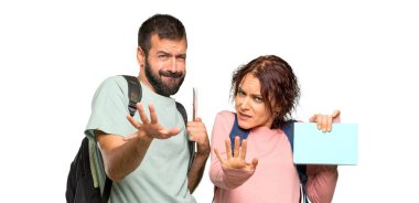 Sırt çantaları ve kitapları olan iki öğrenci biraz gergin ve korkmuş izole beyaz arka plan üzerinde ön elleri germe